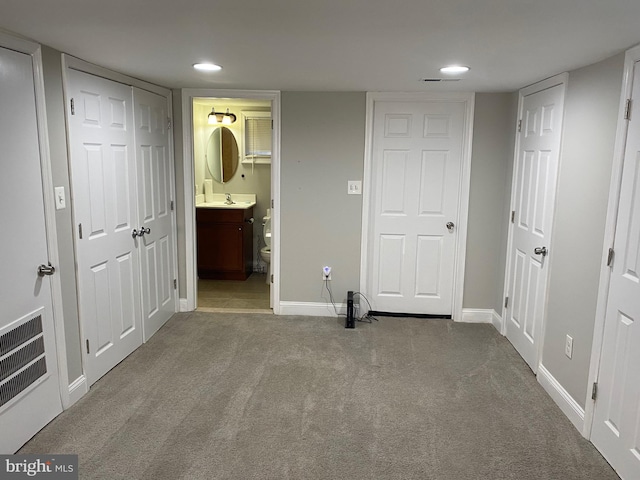 unfurnished bedroom with a sink, visible vents, baseboards, and carpet flooring