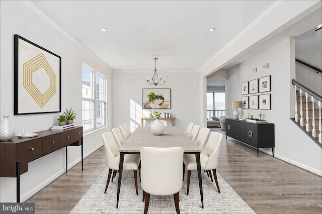 dining space featuring baseboards, ornamental molding, wood finished floors, an inviting chandelier, and stairs