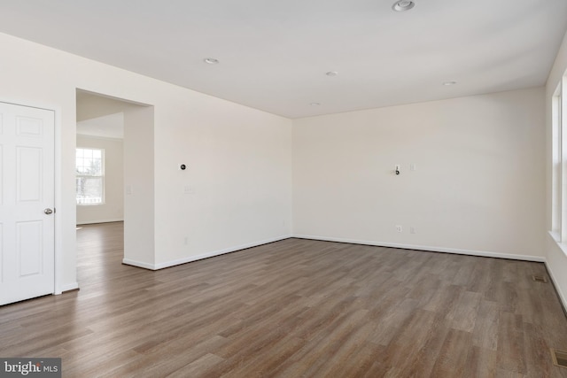 empty room featuring visible vents, baseboards, wood finished floors, and recessed lighting