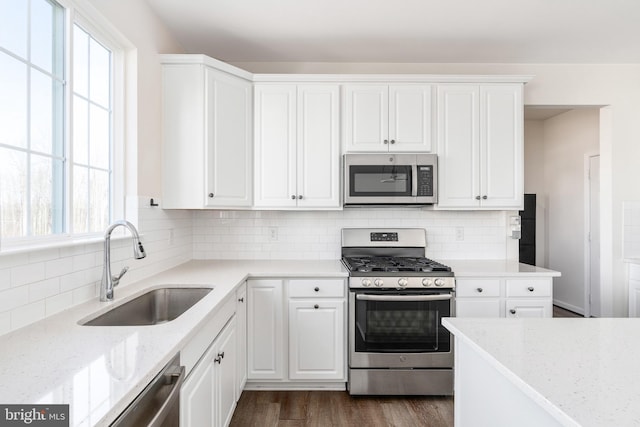 kitchen with stainless steel appliances, a sink, dark wood finished floors, and white cabinetry