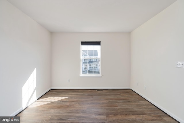 empty room with baseboards, visible vents, and wood finished floors