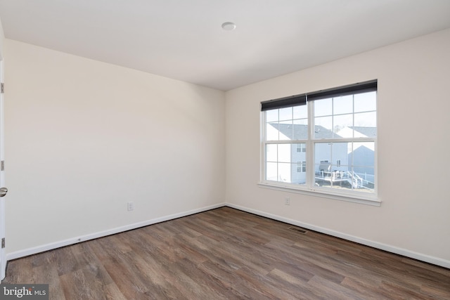 spare room with visible vents, baseboards, and wood finished floors