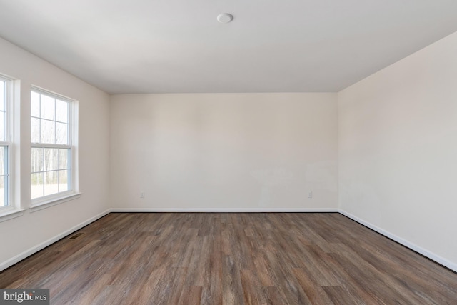 empty room featuring visible vents, baseboards, and wood finished floors