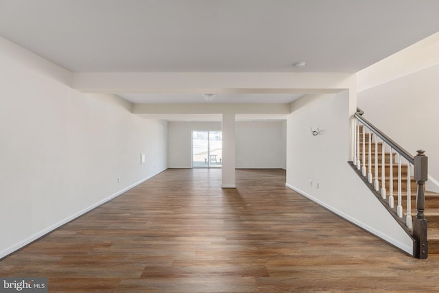 empty room featuring stairs, baseboards, and wood finished floors