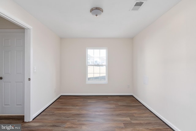 spare room with visible vents, baseboards, and wood finished floors