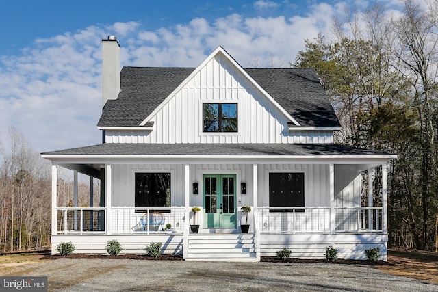 view of front of property with french doors, a chimney, a shingled roof, covered porch, and board and batten siding