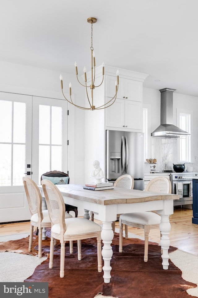 dining space with light wood finished floors and an inviting chandelier