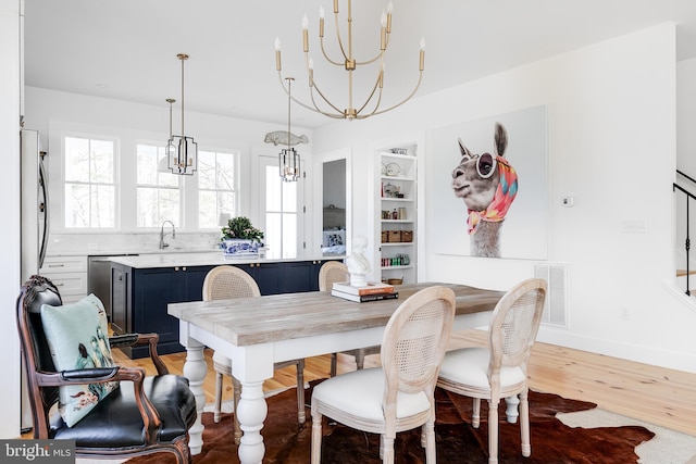 dining space with an inviting chandelier, built in shelves, baseboards, and wood finished floors