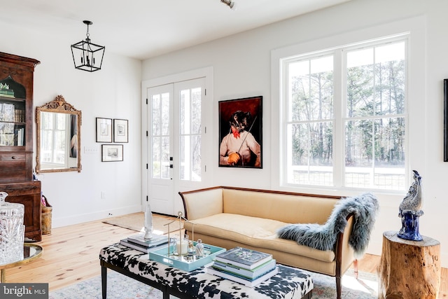 living area with french doors, a notable chandelier, baseboards, and wood finished floors