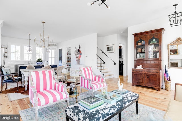 living area with a chandelier, stairway, and light wood-style floors