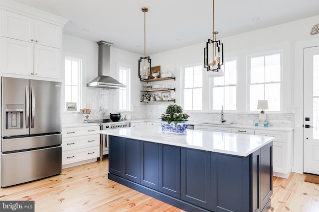 kitchen featuring tasteful backsplash, stainless steel appliances, wall chimney range hood, open shelves, and a sink