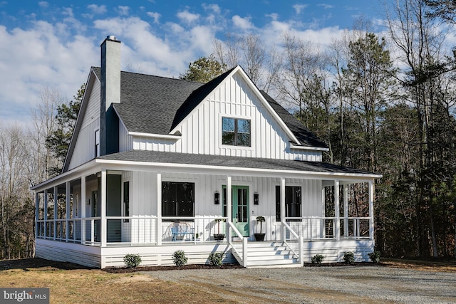 view of front of home with a porch, a chimney, a shingled roof, and board and batten siding