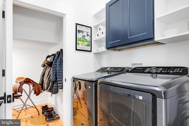 washroom with wood finished floors, washing machine and dryer, cabinet space, and baseboards