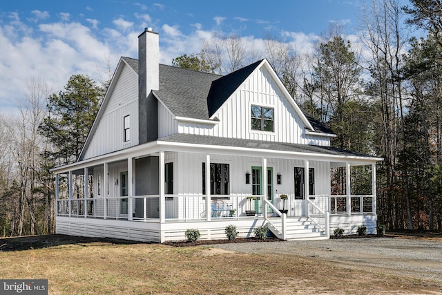 view of front of house featuring board and batten siding, covered porch, roof with shingles, and a chimney