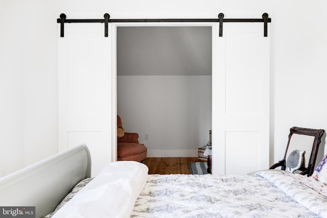 bedroom with wood finished floors and a barn door