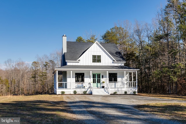 view of front facade featuring covered porch, a shingled roof, board and batten siding, and a chimney