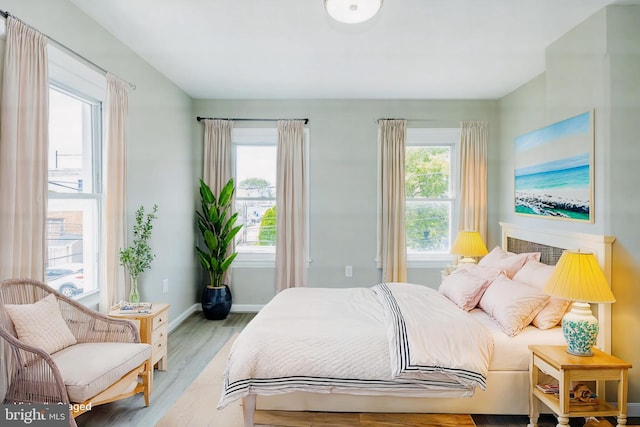 bedroom with light wood-style floors, multiple windows, and baseboards