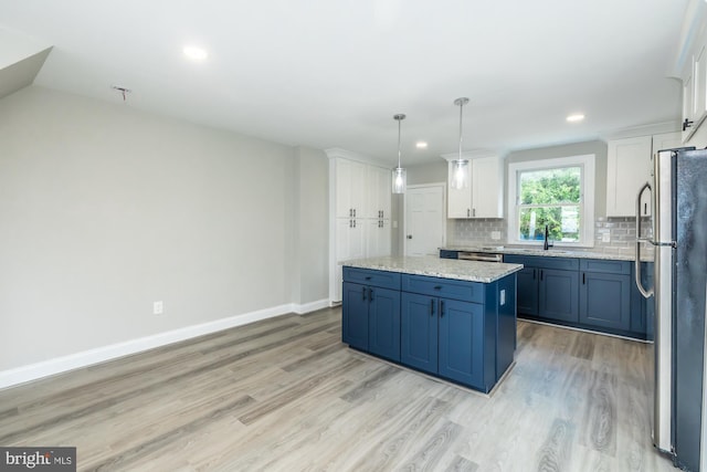 kitchen featuring light wood-style flooring, white cabinetry, baseboards, backsplash, and freestanding refrigerator