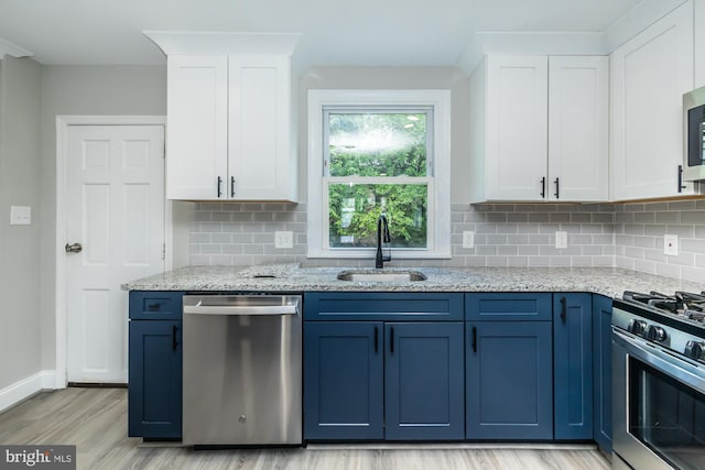 kitchen with stainless steel appliances, white cabinets, a sink, blue cabinets, and light wood-type flooring