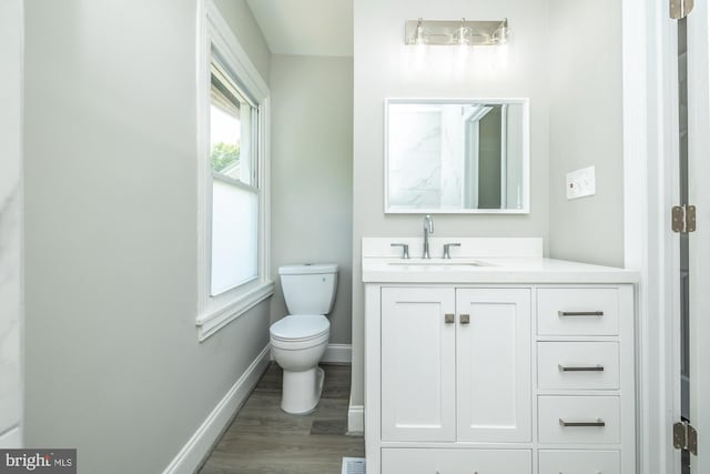 bathroom featuring toilet, vanity, baseboards, and wood finished floors