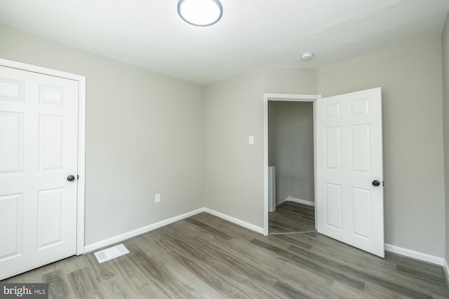 unfurnished bedroom featuring wood finished floors, visible vents, and baseboards