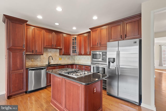 kitchen featuring stainless steel appliances, tasteful backsplash, glass insert cabinets, a sink, and light wood-type flooring