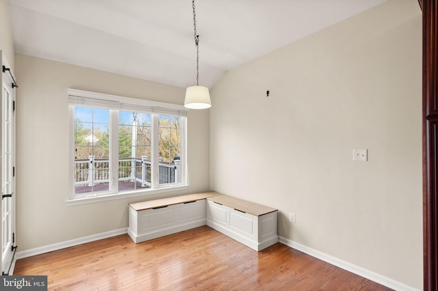 interior space featuring light wood finished floors, baseboards, and vaulted ceiling