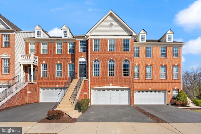 townhome / multi-family property featuring an attached garage, aphalt driveway, and brick siding