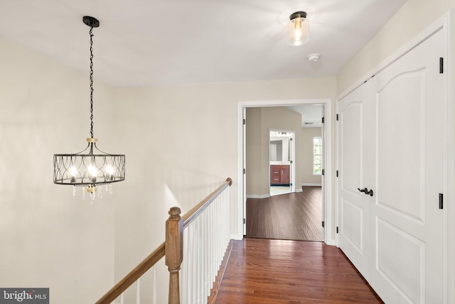 hallway with a notable chandelier, wood finished floors, an upstairs landing, and baseboards