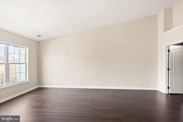 unfurnished room featuring baseboards, visible vents, and dark wood finished floors