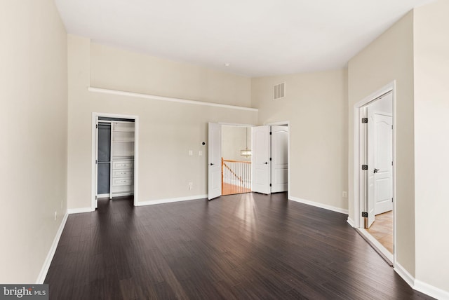 interior space featuring dark wood-type flooring, visible vents, and baseboards