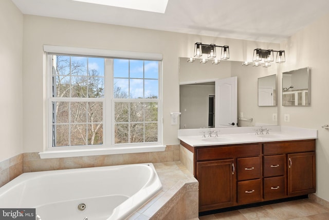 bathroom featuring a skylight, a sink, a whirlpool tub, and double vanity