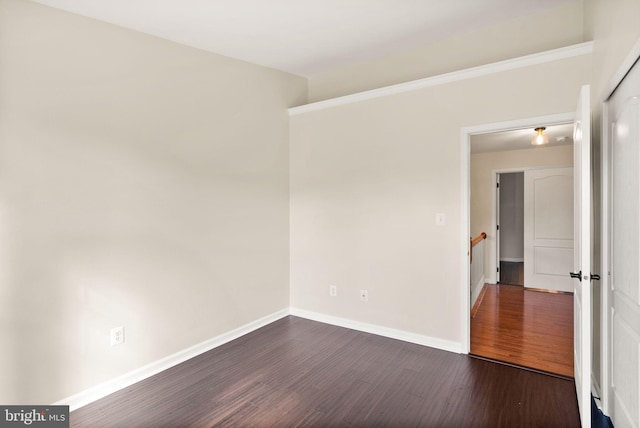 spare room with dark wood-style flooring and baseboards