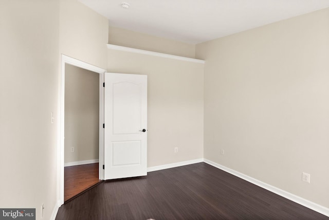 unfurnished room with dark wood-type flooring and baseboards