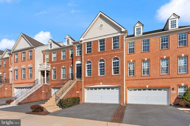 townhome / multi-family property with driveway, a garage, and brick siding