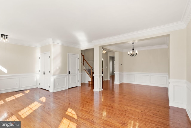 spare room featuring light wood-style flooring, a chandelier, and stairway