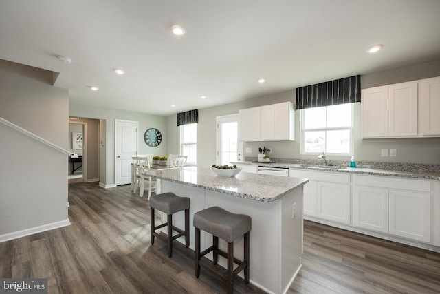 kitchen featuring a kitchen island, a healthy amount of sunlight, white cabinetry, and a sink