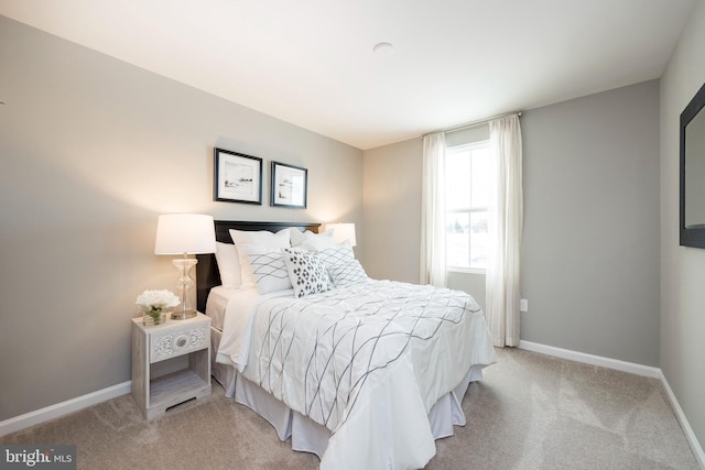 bedroom with light colored carpet and baseboards