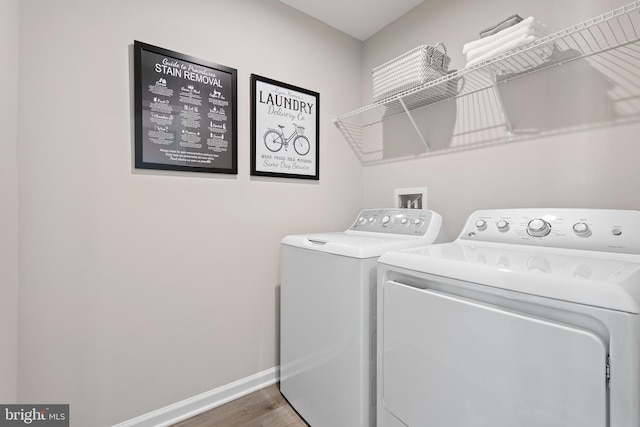 laundry room with laundry area, baseboards, washing machine and clothes dryer, and wood finished floors