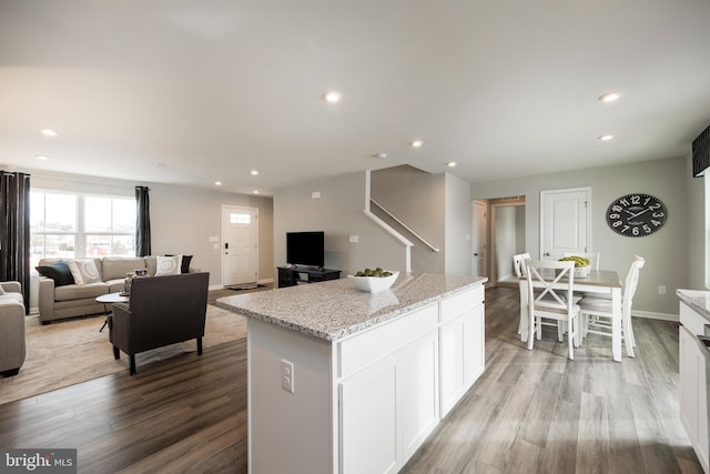 kitchen featuring light wood-type flooring, light stone countertops, a center island, and recessed lighting