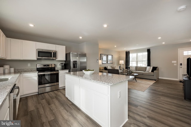 kitchen with appliances with stainless steel finishes, a kitchen island, white cabinets, and recessed lighting