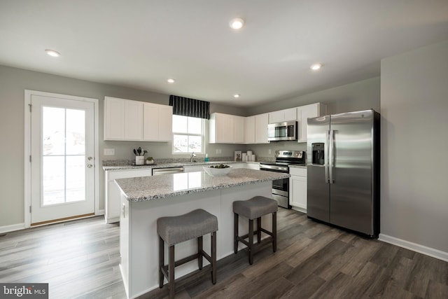 kitchen featuring recessed lighting, stainless steel appliances, a kitchen island, white cabinetry, and dark wood finished floors