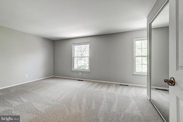 unfurnished room featuring visible vents, carpet, and baseboards