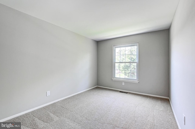 spare room with carpet flooring, baseboards, and visible vents