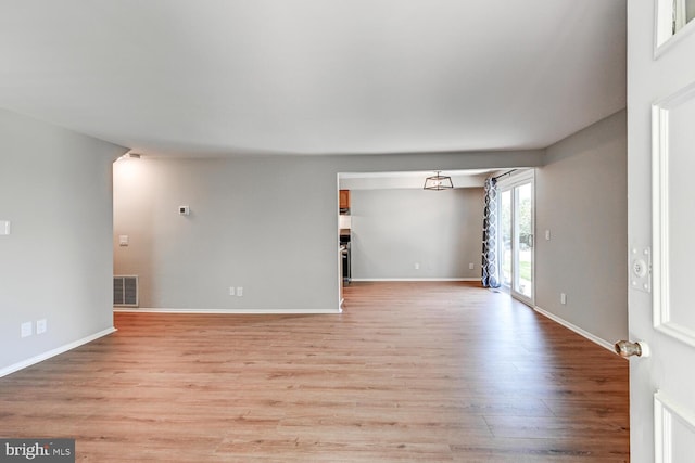 unfurnished living room with baseboards, light wood-type flooring, and visible vents