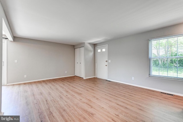 unfurnished living room with visible vents, baseboards, and light wood-type flooring