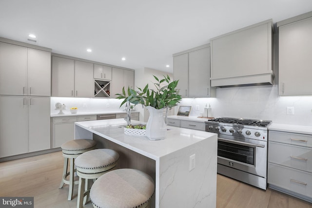 kitchen featuring high end stainless steel range oven, a kitchen breakfast bar, a kitchen island, and gray cabinetry