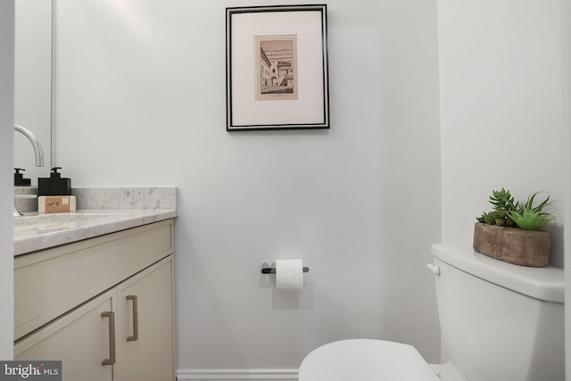 bathroom featuring baseboards, toilet, and vanity