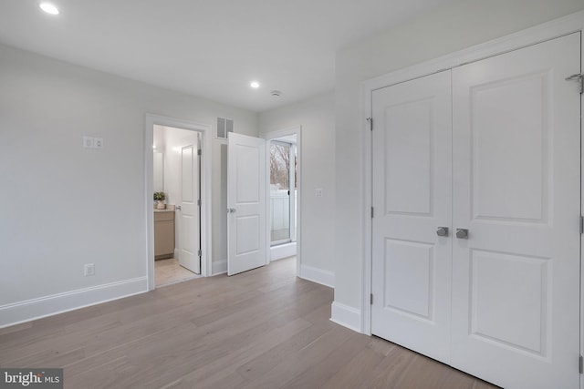 unfurnished bedroom featuring a closet, visible vents, light wood-type flooring, and baseboards