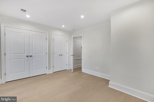 unfurnished bedroom featuring visible vents, baseboards, light wood-style flooring, recessed lighting, and two closets